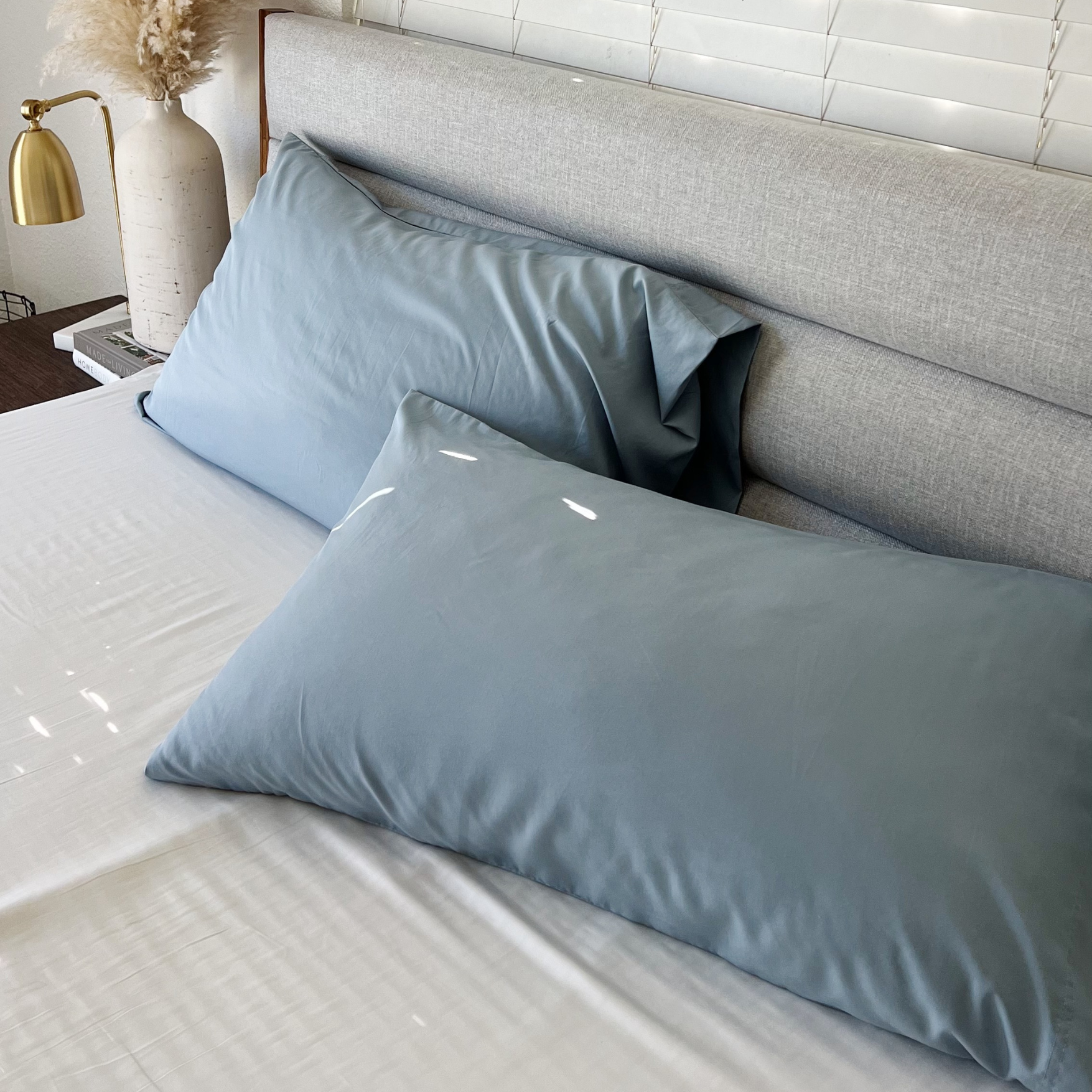 Blue copper infused bamboo pillowcases on a bed with white sheets.
